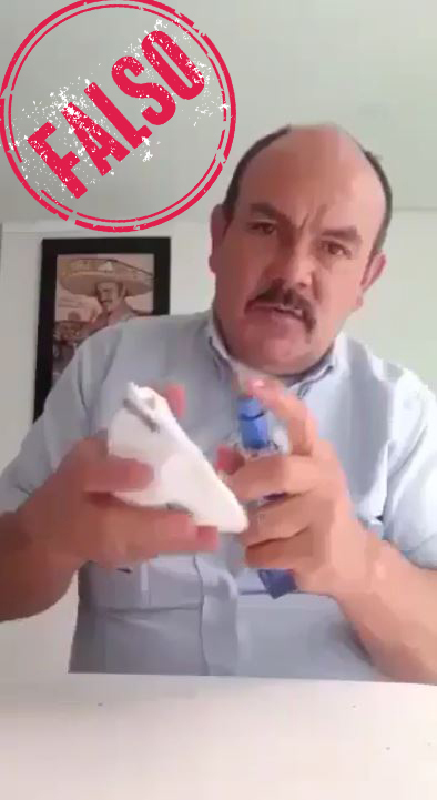 Un hombe remoja su tapabocas en alcohol
